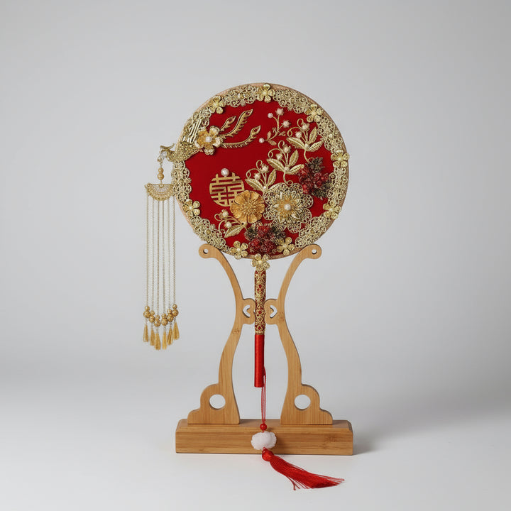 Decorative fan with intricate designs on a wooden stand against a dark background