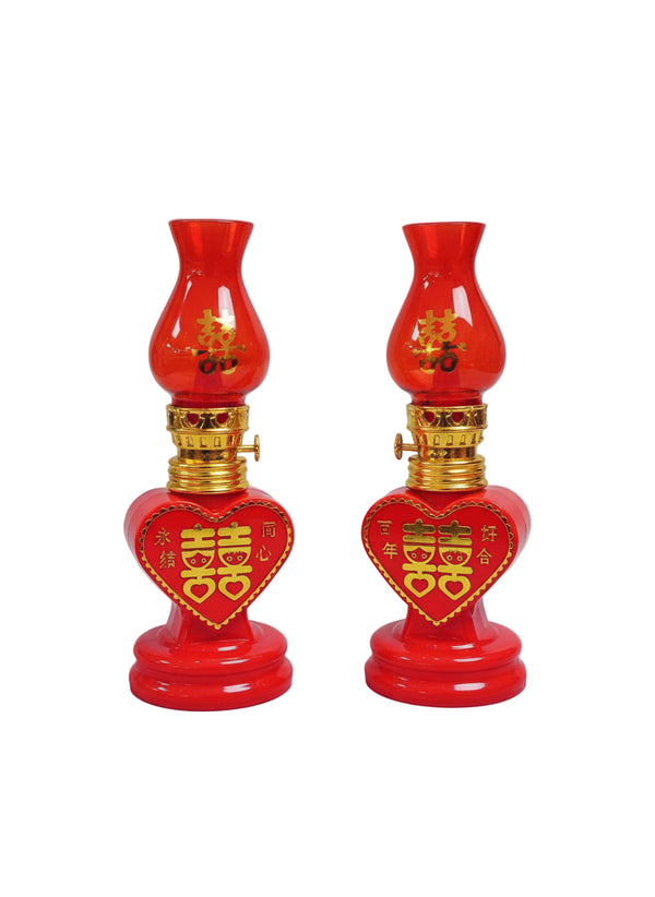 Two red oil lamps with gold accents on a white marble surface.