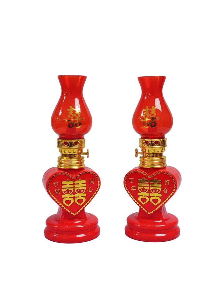 Two red oil lamps with gold accents on a white marble surface.