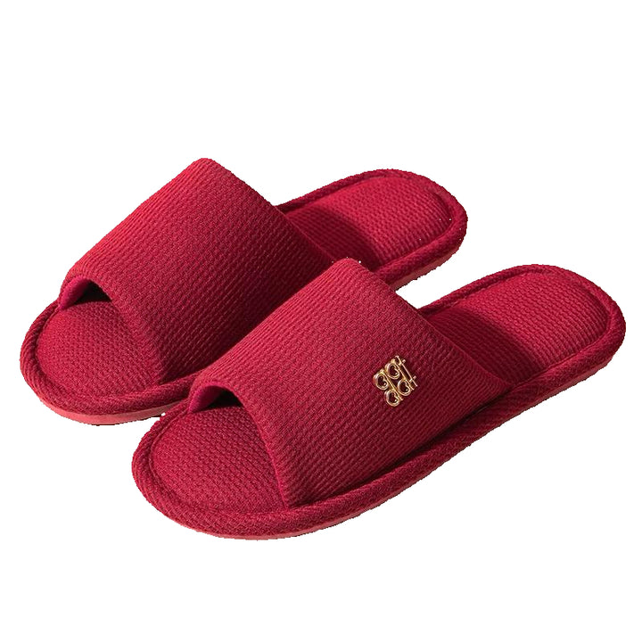 Red slippers with a gold logo on a white background